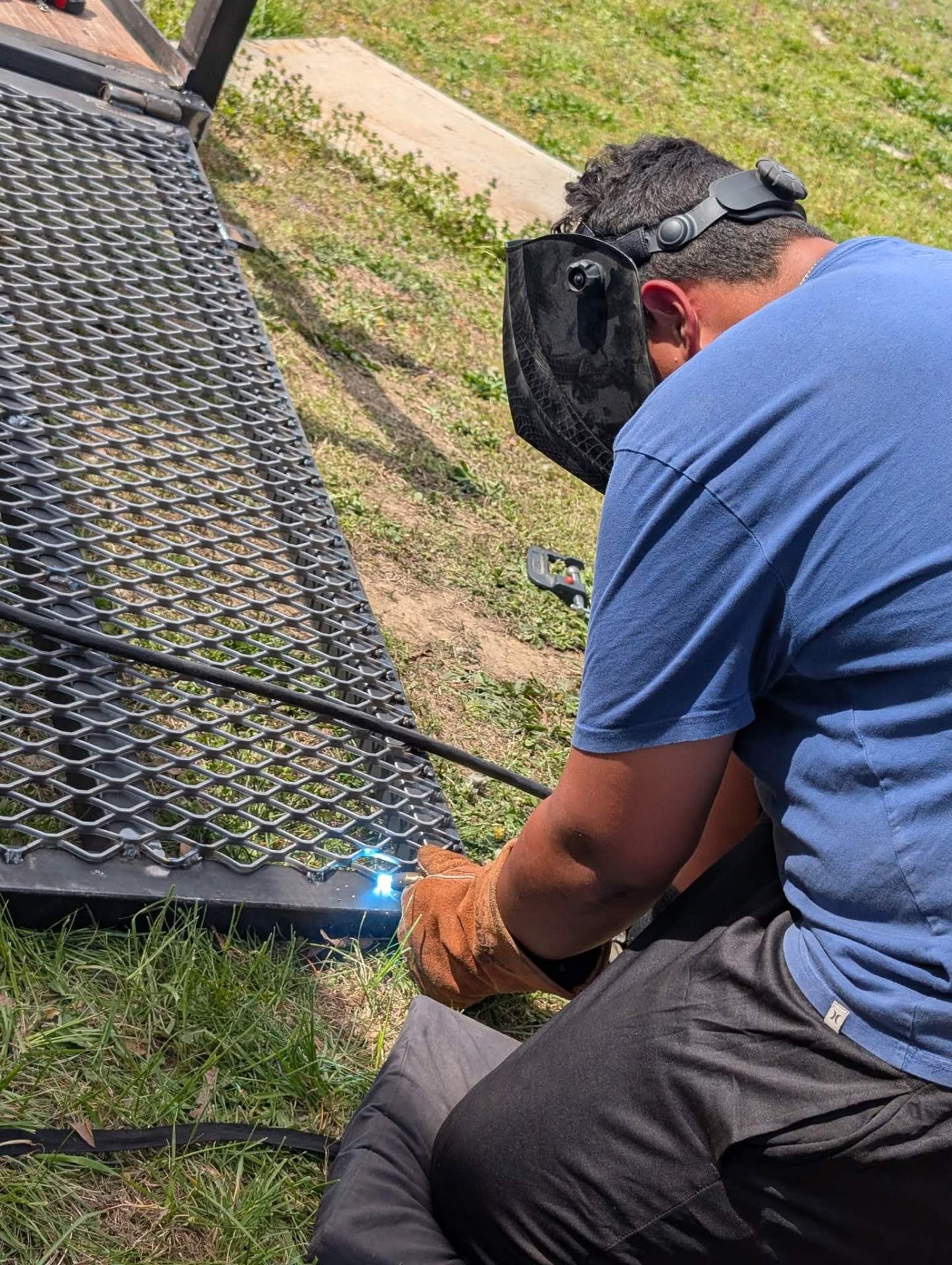 Welder repairing an expanded metal trailer gate